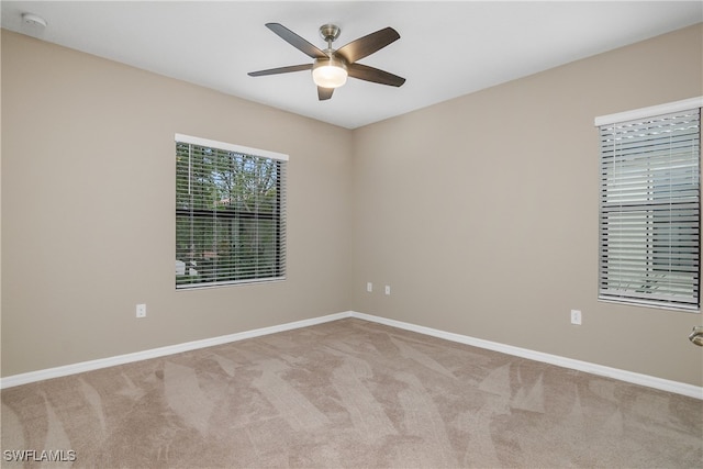 carpeted spare room featuring a ceiling fan and baseboards