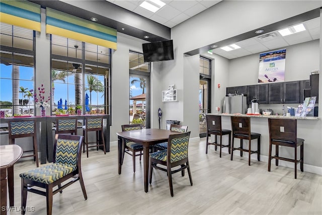 dining space featuring a drop ceiling, visible vents, baseboards, and a towering ceiling