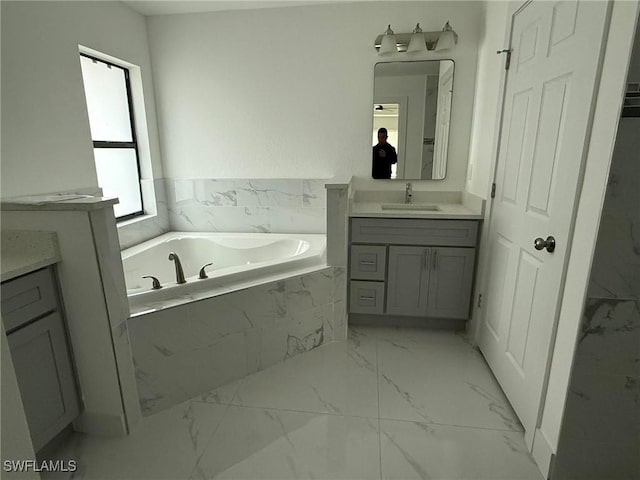 bathroom featuring vanity and tiled tub