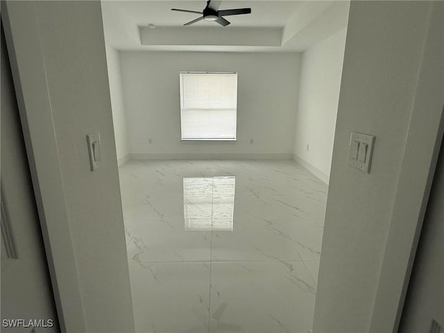 empty room with a raised ceiling and ceiling fan