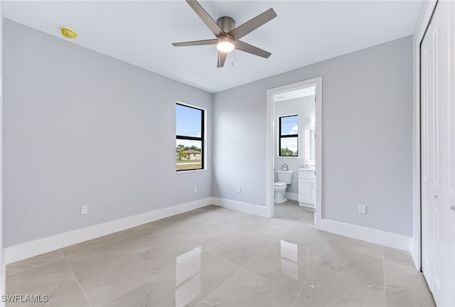 unfurnished bedroom featuring connected bathroom, ceiling fan, and a closet