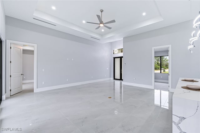 interior space featuring a raised ceiling and ceiling fan