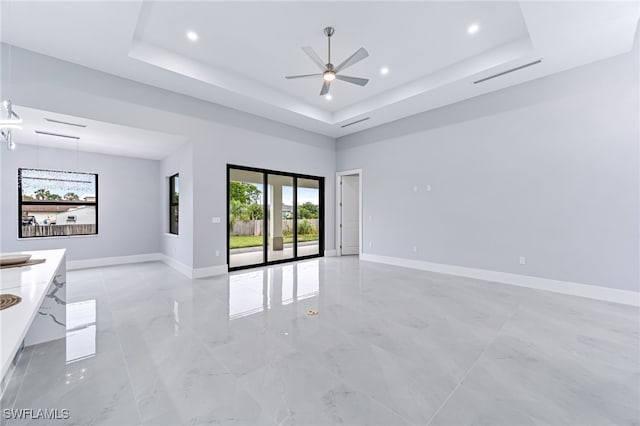 spare room with ceiling fan and a raised ceiling