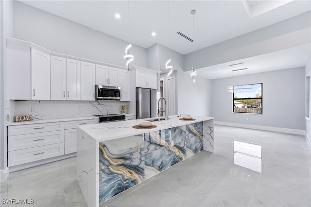 kitchen with appliances with stainless steel finishes, a center island with sink, and white cabinetry