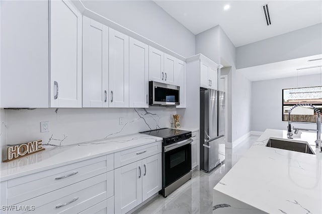 kitchen with light stone countertops, white cabinetry, sink, and stainless steel appliances