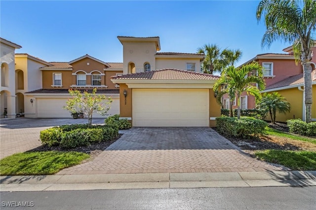 mediterranean / spanish-style home featuring a garage, decorative driveway, and stucco siding