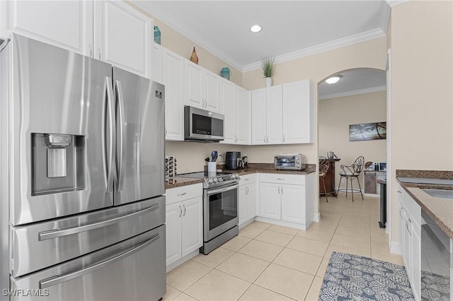 kitchen with appliances with stainless steel finishes, white cabinetry, ornamental molding, and light tile patterned floors