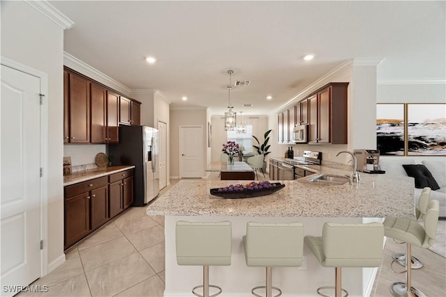 kitchen with sink, light stone counters, crown molding, hanging light fixtures, and stainless steel appliances