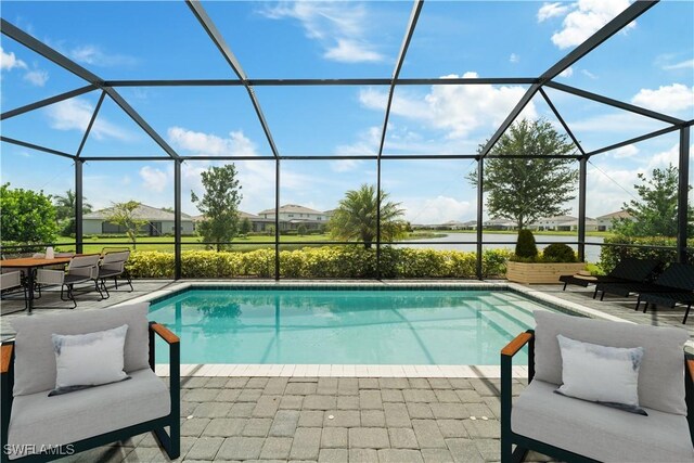 view of swimming pool with a water view, glass enclosure, and a patio area