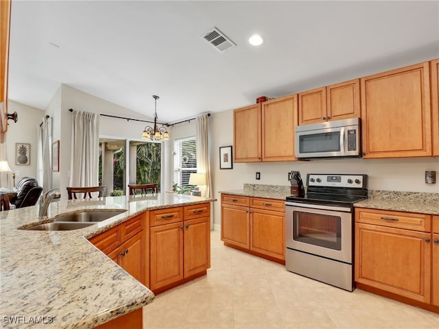 kitchen featuring sink, light stone counters, decorative light fixtures, vaulted ceiling, and stainless steel appliances