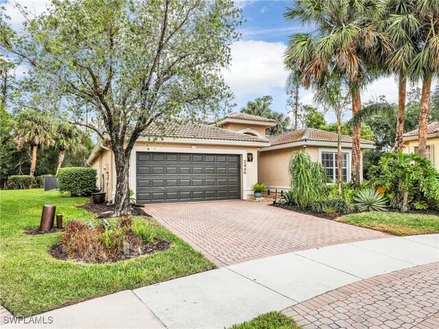 view of front of home featuring a front lawn, stucco siding, a tile roof, decorative driveway, and a garage