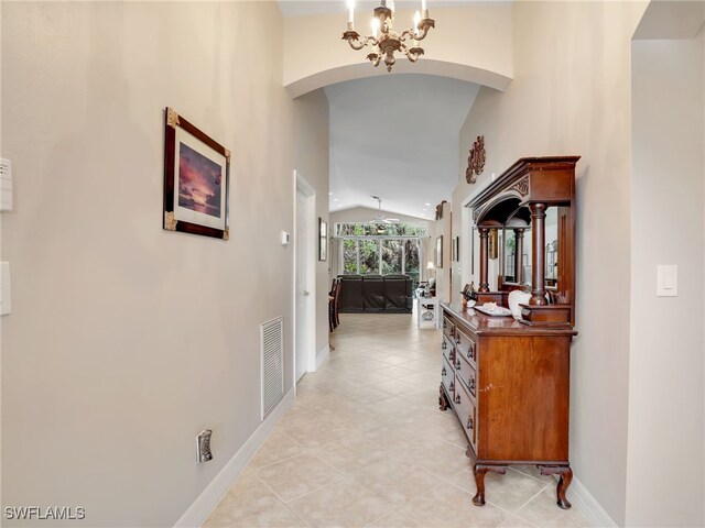 hall with arched walkways, light tile patterned flooring, vaulted ceiling, visible vents, and a chandelier