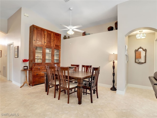 tiled dining area with ceiling fan and a high ceiling