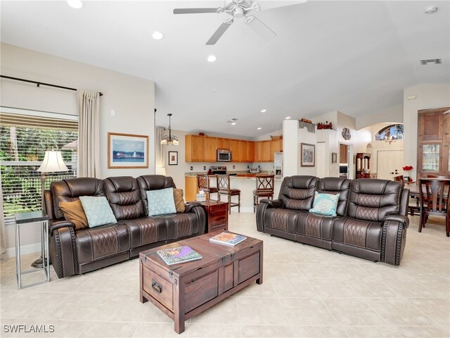 living room featuring lofted ceiling, visible vents, light tile patterned floors, and ceiling fan with notable chandelier