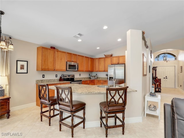 kitchen with vaulted ceiling, pendant lighting, a breakfast bar area, a notable chandelier, and stainless steel appliances