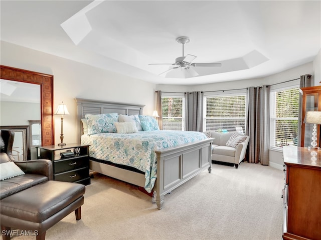 carpeted bedroom with multiple windows, a tray ceiling, and ceiling fan