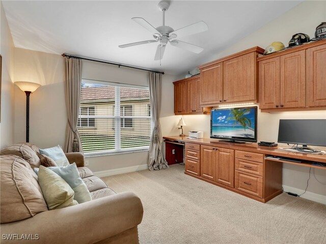 home office with built in study area, a ceiling fan, baseboards, and light carpet