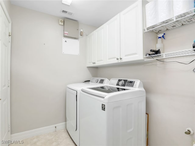 laundry room featuring washing machine and dryer, cabinets, and light tile patterned flooring