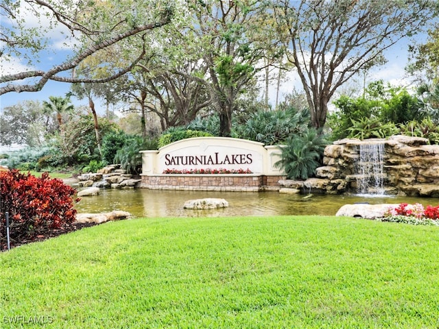 community sign featuring a water view and a lawn