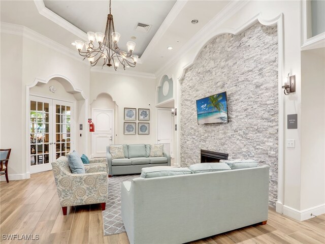 living room featuring ornamental molding, a tray ceiling, visible vents, and light wood-style flooring