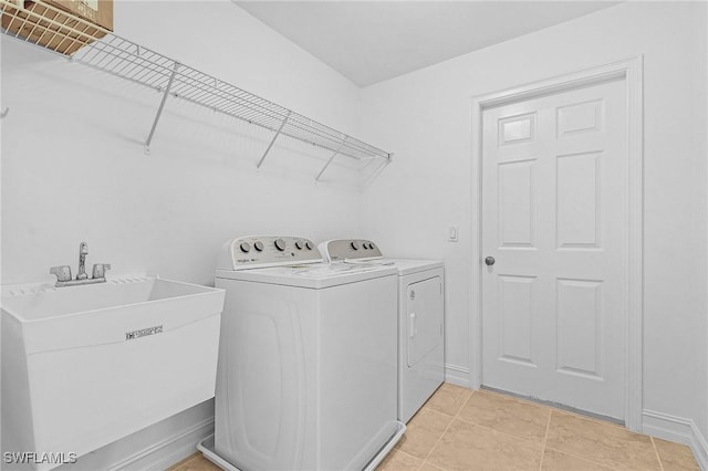 washroom with light tile patterned floors, washer and dryer, and sink