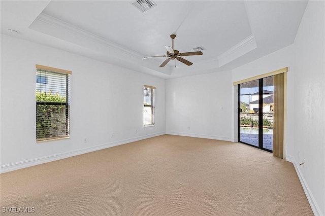 carpeted empty room with a raised ceiling, ceiling fan, and ornamental molding