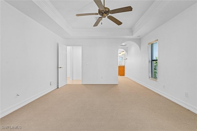 spare room featuring ceiling fan, crown molding, a tray ceiling, and light carpet