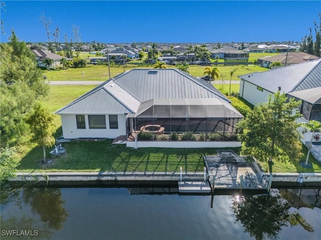 back of house featuring a lanai, a yard, and a water view