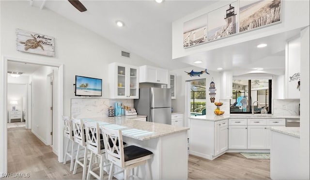 kitchen with white cabinets, appliances with stainless steel finishes, tasteful backsplash, and vaulted ceiling