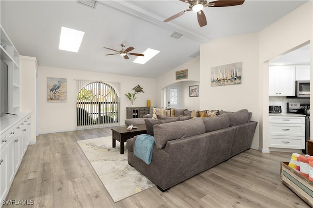 living room featuring ceiling fan, light wood-type flooring, and lofted ceiling with skylight