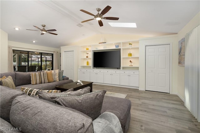 living room with vaulted ceiling with skylight, ceiling fan, and light hardwood / wood-style floors