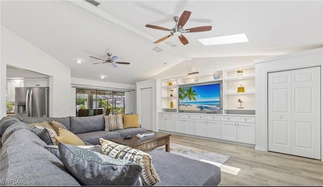 living room featuring ceiling fan, vaulted ceiling with skylight, and light hardwood / wood-style flooring