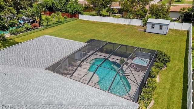 view of pool featuring a lawn, glass enclosure, and an outdoor structure