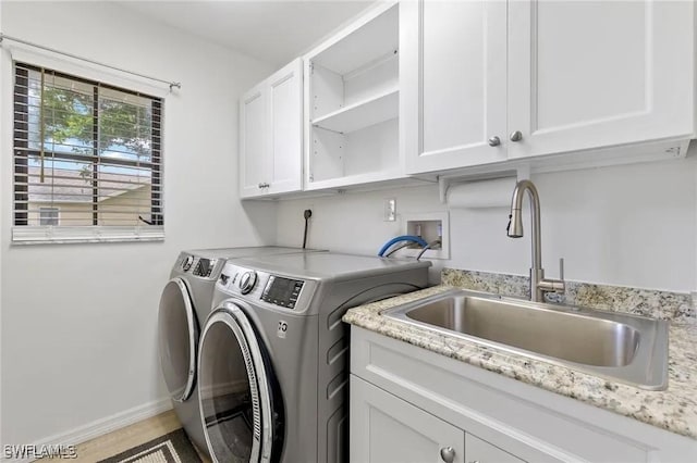 laundry room featuring washing machine and dryer, sink, and cabinets