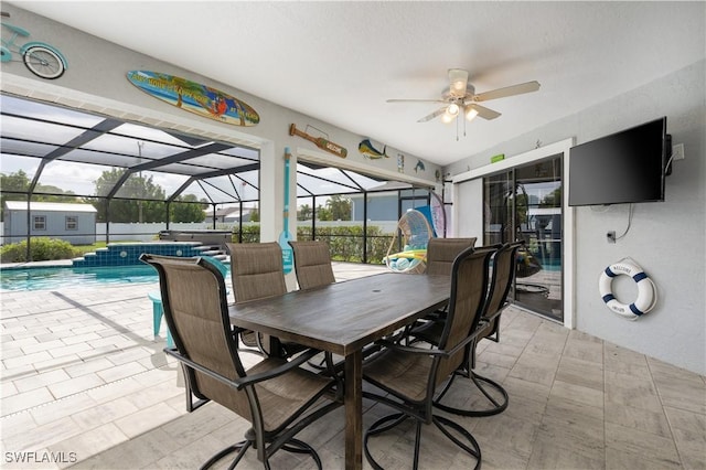 view of patio / terrace with a lanai, ceiling fan, a swimming pool with hot tub, and pool water feature