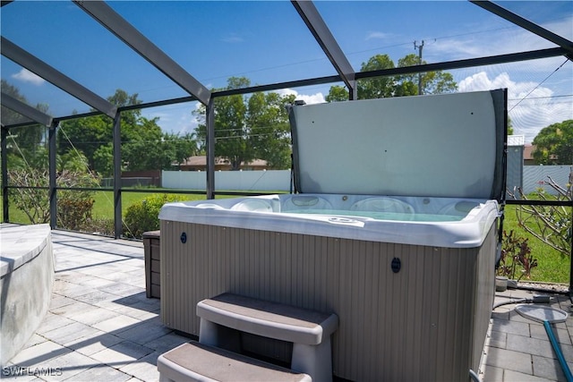 view of patio / terrace featuring a hot tub and a lanai