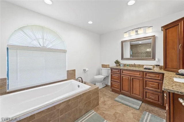 bathroom featuring vanity, tiled bath, and toilet