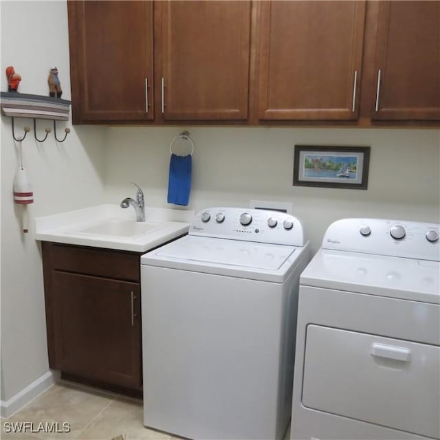 laundry room featuring sink, light tile patterned floors, washer and clothes dryer, and cabinets