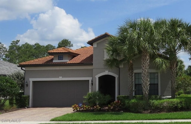 8874 Horned Lark Dr, Naples, FL 34120 - mediterranean / spanish-style house featuring a tile roof, stucco siding, an attached garage, and driveway
