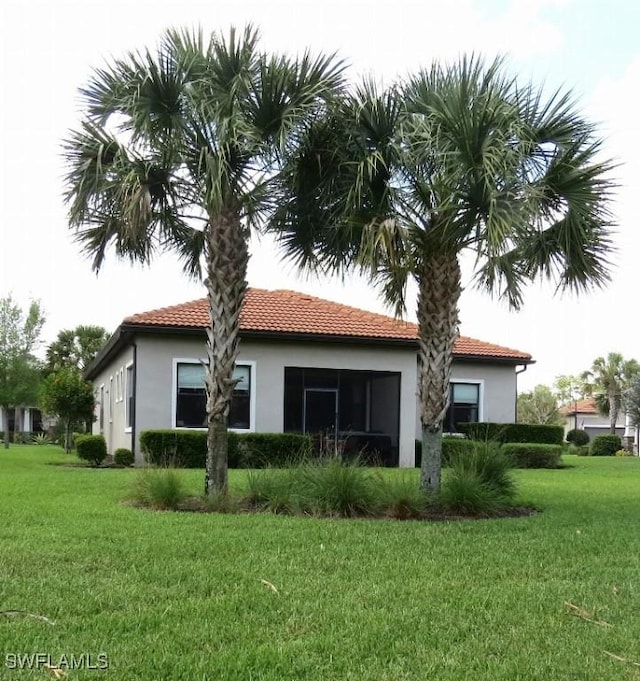 8874 Horned Lark Dr, Naples, FL 34120 - back of house featuring a tile roof, stucco siding, and a lawn
