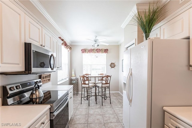 kitchen with white cabinetry, ceiling fan, appliances with stainless steel finishes, light tile patterned flooring, and crown molding