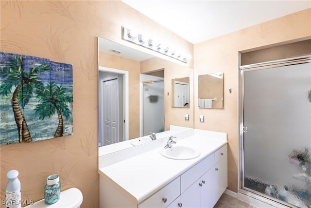 bathroom with a shower with door, vanity, and toilet