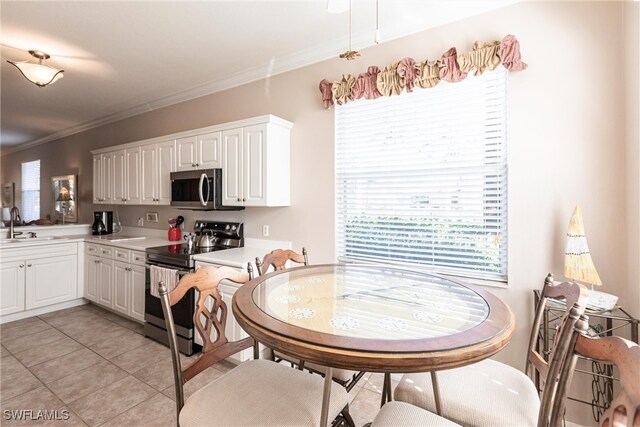 kitchen with white cabinetry, appliances with stainless steel finishes, ornamental molding, and sink