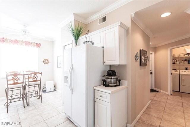 kitchen with white cabinetry, independent washer and dryer, ornamental molding, and white fridge with ice dispenser