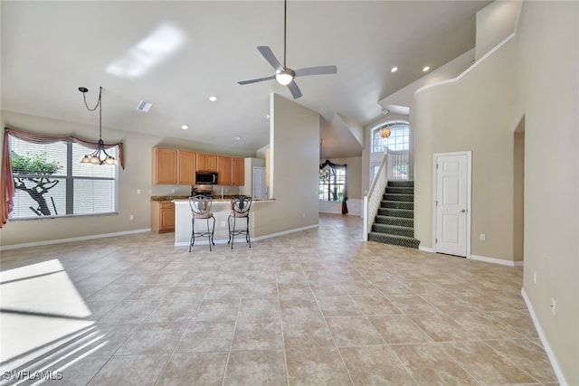 unfurnished living room featuring light tile patterned floors, high vaulted ceiling, and ceiling fan