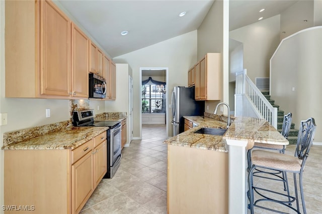 kitchen with sink, a kitchen breakfast bar, stainless steel appliances, kitchen peninsula, and light brown cabinets