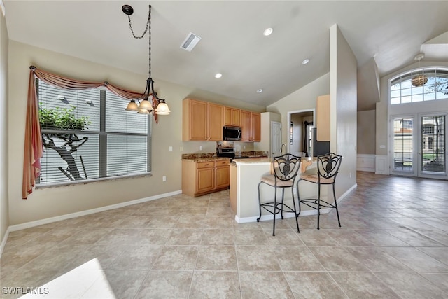 kitchen featuring a breakfast bar, light stone counters, decorative light fixtures, vaulted ceiling, and appliances with stainless steel finishes