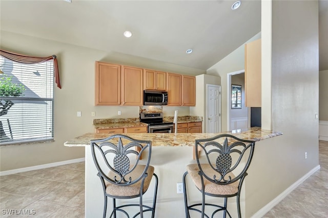 kitchen featuring light tile patterned floors, appliances with stainless steel finishes, a kitchen breakfast bar, kitchen peninsula, and light stone countertops