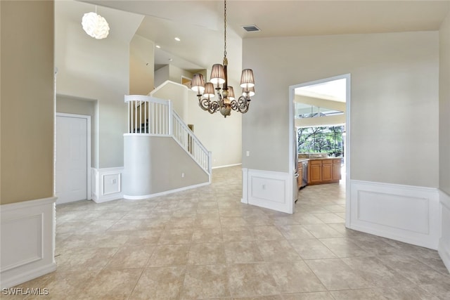 empty room with light tile patterned flooring, lofted ceiling, and an inviting chandelier