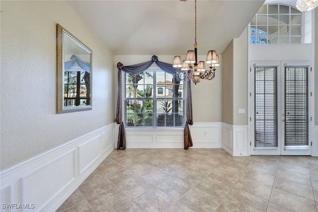 unfurnished dining area featuring light tile patterned floors, an inviting chandelier, and french doors